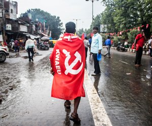 A member of the Kerala Water Authority Employees Union marches with the flag draped around his shoulders.