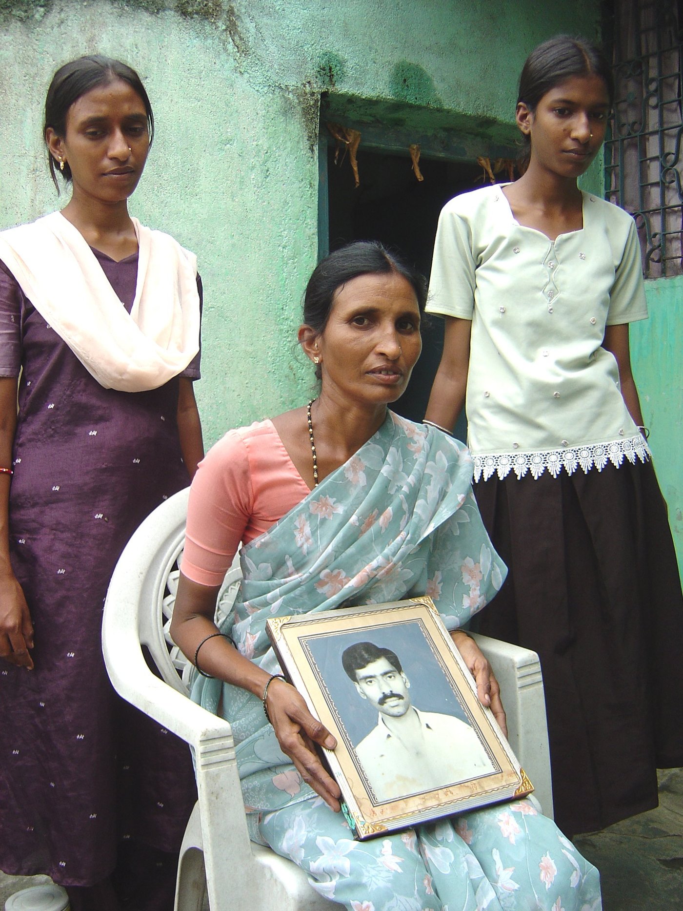 Saraswati Amberwar sitting with a photo of her deceased husband