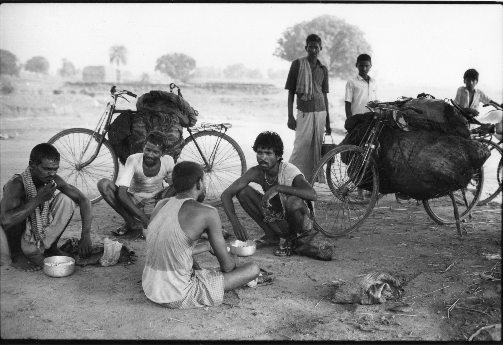 Group of men from different castes eating lunch beside their coal laden cycles