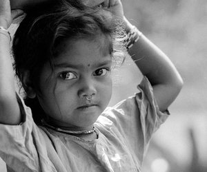 A young girl carrying utensils on her head