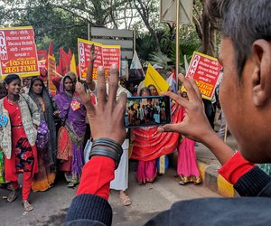 A young boy takes a phone video of his mother marching to Jantar Mantar.